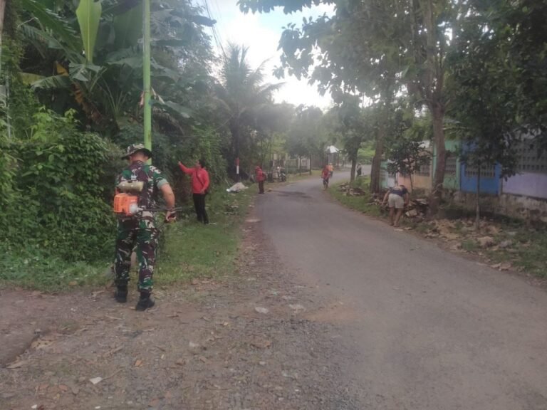 Babinsa Koramil Rogojampi Gandeng Warga Timurejo Bersihkan Rumput Liar di Bahu Jalan